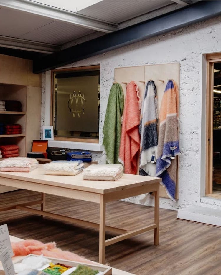 Cushendale show room interior, Scarves folded on a table and hanging off pegs on a wall behind