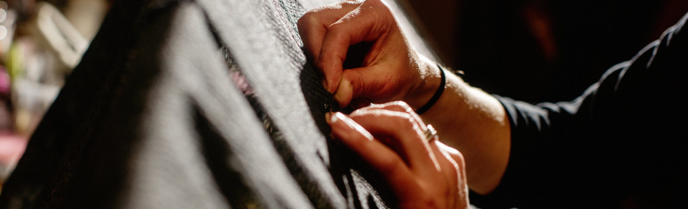 Hands stitching and repairing a piece of brown fabric