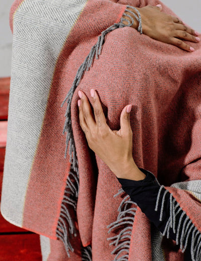 Dancer with red and grey woollen blanket over her head holds her head with her hand