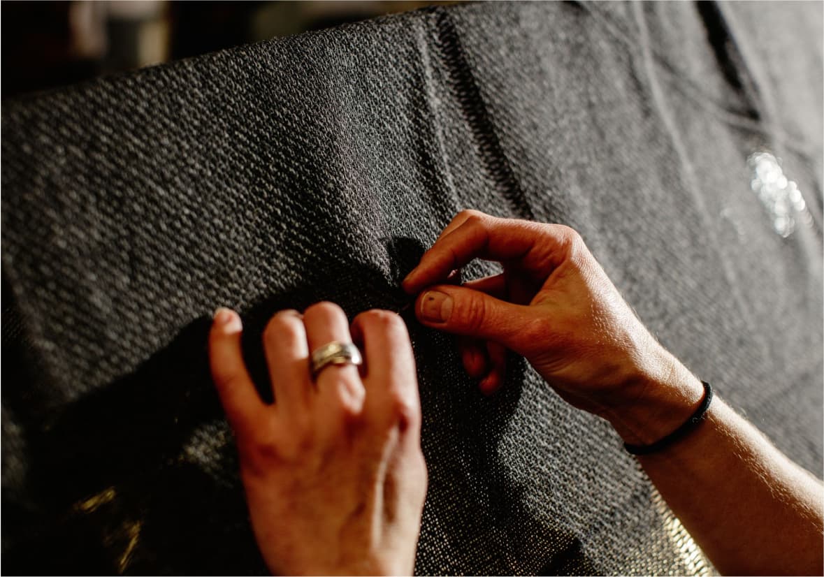 Hands stitching and repairing a piece of fabric